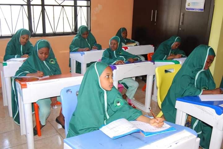 Primary girls in green uniform attentively learning at their desks